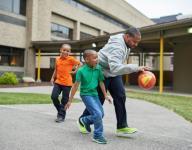 A father and two young boys play with a ball.